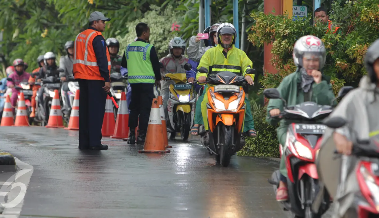 Petugas mengamati pengendara sepeda motor yang masuk menuju tol dalam kota di pintu tol Taman Mini 2, Jakarta, Kamis (21/4). Hujan deras yang mengguyur sejak semalam membuat sejumlah jalan di Ibu Kota tergenang banjir. (Liputan6.com/Angga Yuniar)