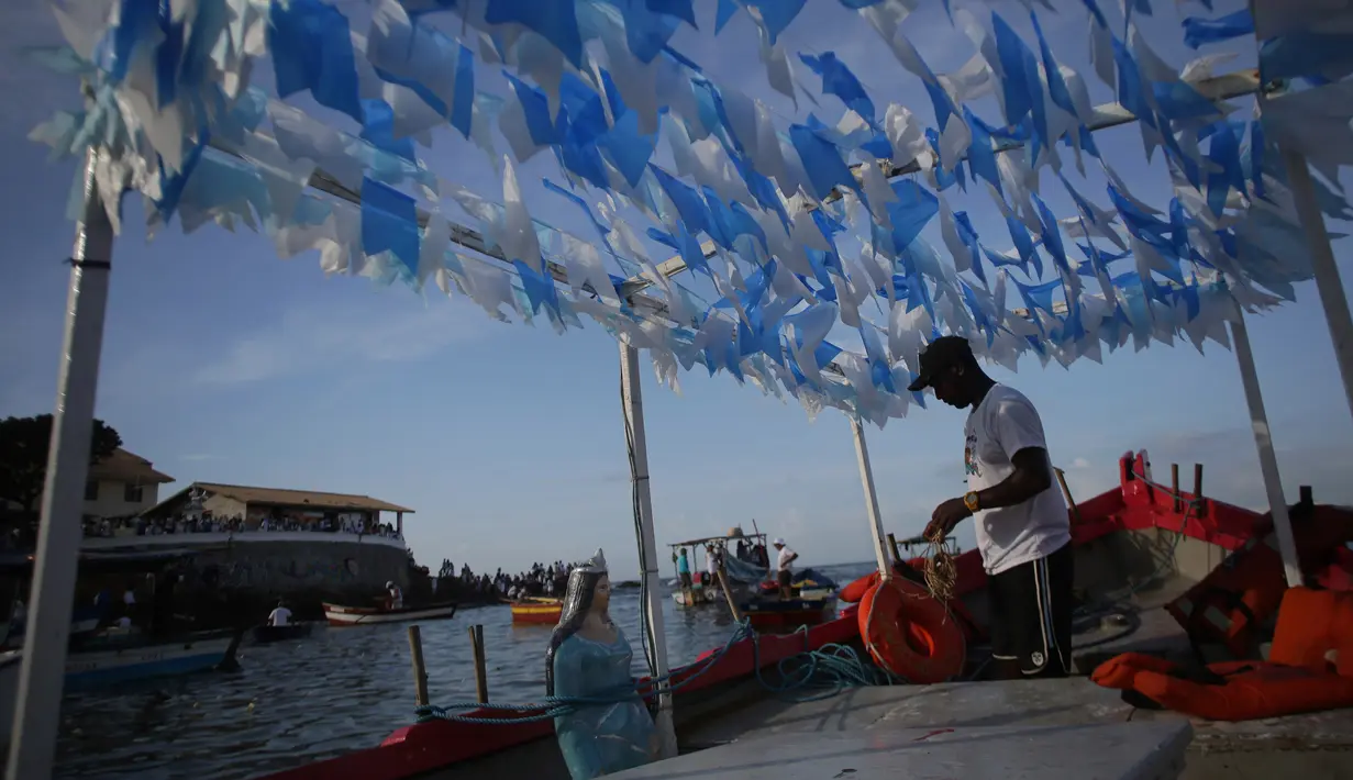 Seorang nelayan mempersiapkan kapalnya untuk membawa persembahan ke laut saat perayaan Dewi Laut Yemanja di Salvador, Brasil (2/2). Dalam ritual ini mereka meminta perlindungan kepada Dewi Laut. (AP Photo / Eraldo Peres)