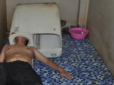 Seorang pria tergeletak di lantai dengan kepala yang terjebak di dalam mesin cuci di Fuqing, China, 29 Mei 2016. Kejadian tersebut dialami ketika pria malang itu memasukkan kepala saat memperbaiki mesin yang tengah menyala. (REUTERS/Stringer)