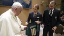 Pelatih Italia, Roberto Mancini (tengah) memberikan jersey Timnas Italia kepada Paus Fransiskus saat mengikuti misa kanonisasi untuk John Henry Newman dari Inggris, Giuseppina Vannini dari Italia, Maria Teresa Chiramel Mankidiyan dari India, Dulce Lopes Pontes dari Brasil, dan Margarita Bays dari Swiss di Vatikan pada 13 Oktober 2019. (AFP/Vatican Media)