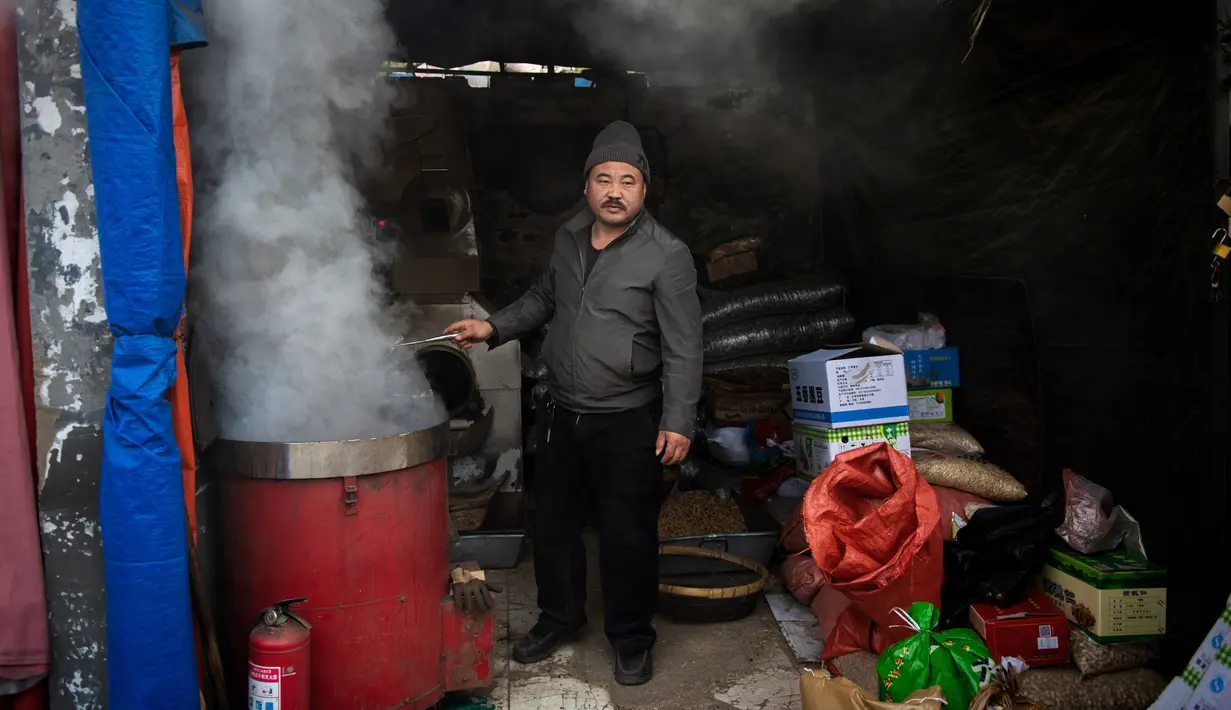 Seorang pekerja memasak chestnut di pasar di Beijing (20/11). (AFP Photo/Nicolas Asfouri)