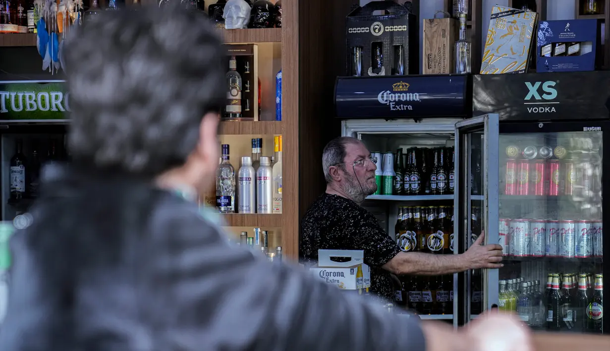 Seorang pria membuka lemari pendingin berisi minuman beralkohol di sebuah toko minuman keras di Baghdad, Irak, Kamis, 9 Maret 2023. Larangan minuman beralkohol di Irak mendapat kritik anggota parlemen beragama Kristen. (AP Photo/Hadi Mizban)