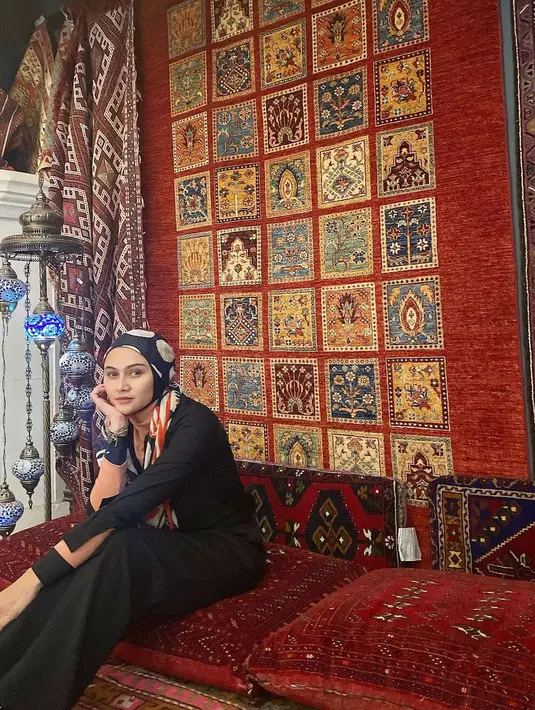 Berpose dengan latar belakang karpet dan bantal, Zee Zee terlihat memesona memadukan cardigan, turtleneck top, dan celana kulot. Gaya hijab yang dibentuk turban membuat penampilannya makin terlihat memesona. (Instagram/zeezeeshahab).