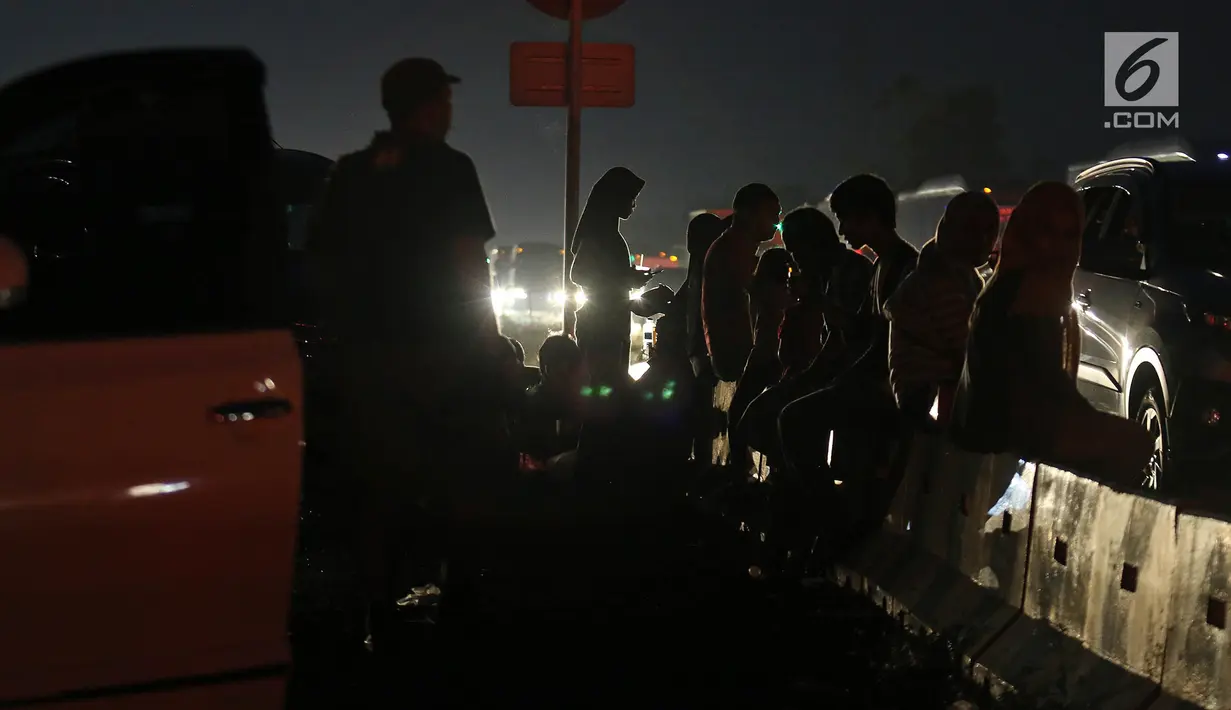 Pemudik menikmati makanan untuk berbuka puasa sembari beristirahat di pinggir ruas jalan tol Cipali KM 187, Kabupaten Cirebon, Jawa Barat, Kamis (30/5/2019). Sejumlah pemudik memilih menggunakan bahu jalan ruas tol untuk berbuka puasa karena penuhnya rest area. (Liputan6.com/Herman Zakharia)