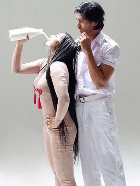 Terlihat Denada sedang menyiramkan tubuhnya dengan sebotol air hingga membuat tubuhnya basah. Ia pun berdiri di depan seorang pria berbaju putih. (Instagram/denadaindonesia)