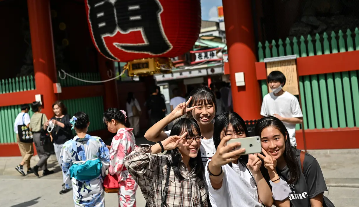 Orang-orang berselfie di pintu masuk kuil Sensoji di distrik Asakusa Tokyo (22/9/2020). Lokasi Kuil Sensoji ini sangat mudah dijangkau. Sebab, ada tak kurang dari empat stasiun yang melintasi Asakusa. (AFP/Charly Triballeau)