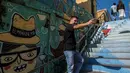 Seorang turis selfie di depan mural jalanan di Valparaiso, Chile, 22 April 2019. Grafiti yang dipadukan seni mural menjadi evolusi baru di galeri seni terbuka Valparaiso. (Martin BERNETTI/AFP)