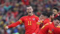 Penyerang Wales, Wales Gareth Bale dan rekan-rekannya melakukan selebrasi usai berhasil lolos ke Piala Dunia 2022 setelah kalahkan Ukraina dalam pertandingan playoff kualifikasi Piala Dunia di Stadion Cardiff City, Cardiff, Wales, Minggu (5/6/2022). Wales menang atas Ukraina dengan skor tipis 1-0. (AFP Photo/Geoff Caddick)