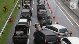 Seorang pedagang asongan menawarkan dagangan kepada pengendara di jalan tol Jagorawi yang sedang menanti waktu buka tutup jalur menuju kawasan wisata puncak, Bogor, Jawa Barat, Sabtu (31/10/2020). (Liputan6.com/Helmi Fithriansyah)