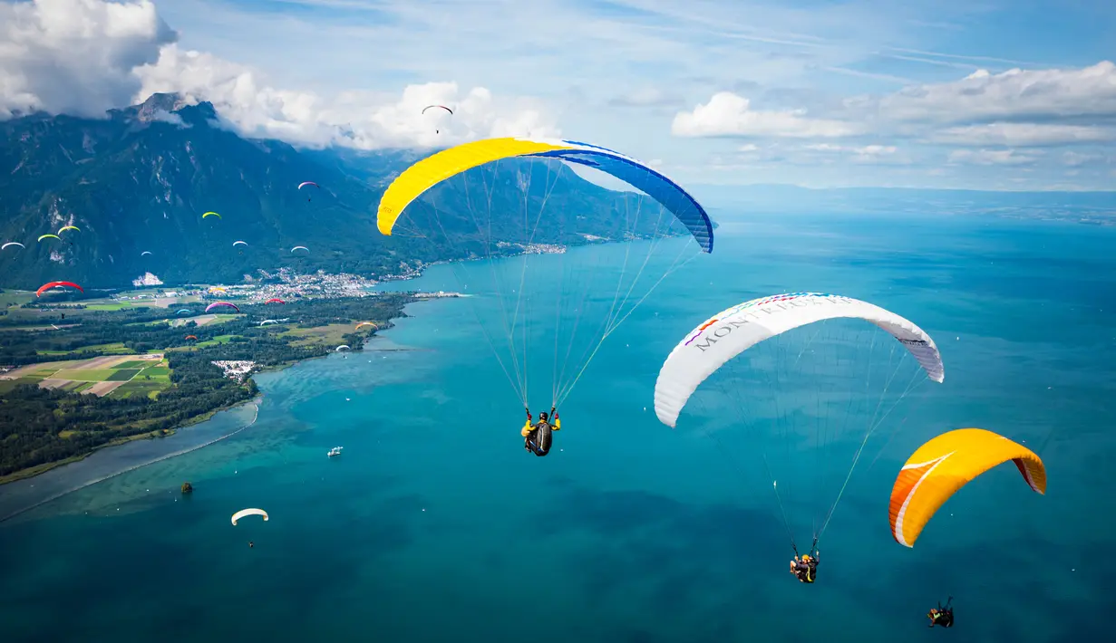 Pemandangan Danau Jenewa yang dihiasi warna-warni dari paraglider yang melakukan penerbangan di Villeneuve, Swiss (20/8). Olahraga paragliding lepas landas dari sebuah lereng bukit atau gunung dengan memanfaatkan angin. (Valentin Flauraud Keystone via AP)