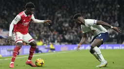 Pemain Arsenal, Bukayo Saka berusaha melewati pemain Tottenham Hotspur, Ryan Sessegnon pada pertandingan lanjutan Liga Inggris di Stadion Tottenham Hotspur di London, Inggris, Minggu (15/1/2023). Hasil ini membuat Arsenal makin kokoh di puncak klasemen dengan koleksi 47 angka dari 18 laga. (AP Photo/Frank Augstein)