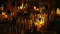 Kerabat bersiap bermalam di samping makam orang tercinta pada perayaan Hari Kematian di pemakaman Arocutin, Michoacan, Meksiko, 1 November 2021. Dalam tradisi ini keluarga menghias makam serta bermalam di kuburan menemani orang tercinta yang telah meninggal. (AP Photo/Eduardo Verdugo)