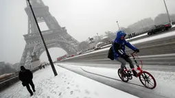 Seorang pengendara melintas saat turun salju di Paris, Prancis, (6/2). Sebelumnya Paris mengalami banjir bandang  akibat meluap Sungai Seine yang dipicu oleh curah hujan tinggi. (AP Photo / Francois Mori)