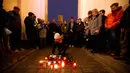 Seorang wanita meletakkan lilin saat berkabung untuk para korban penembakan brutal di Hanau di Gerbang Brandenburg Berlin, Jerman, Kamis (20/2/2020). Tersangka penembakan diketahui bernama Tobias R (43) yang diduga memiliki 'pola pikir yang sangat rasis'. (AP Photo/Markus Schreiber)
