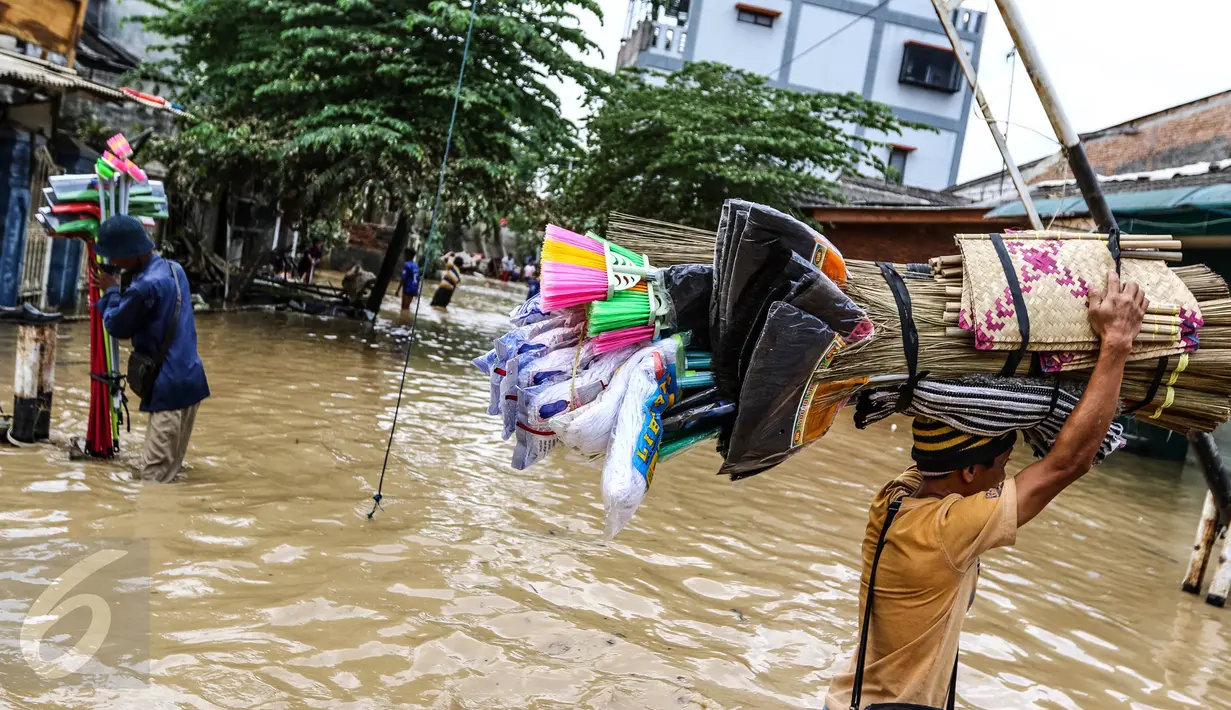 Pedagang penjual alat kebersihan melewati banjir untuk masuk ke kompleks Pondok Gede Permai, Jatiasih, Bekasi, Jumat (22/4). Mereka menjajakan dagangannya berupa alat kebersihan ketika banjir di  kawasan tersebut mulai surut. (Liputan6.com/Fery Pradolo)