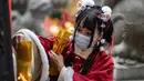 Seorang perempuan yang mengenakan pakaian tradisional mengunjungi kuil Ma Zhu Miao pada hari pertama Tahun Baru Imlek di daerah Pecinan Yokohama Prefektur Kanagawa, dekat Tokyo, Jumat (12/2/2021). Yokohama Chinatown adalah kawasan pecinan terbesar di Jepang. (Philip FONG / AFP)