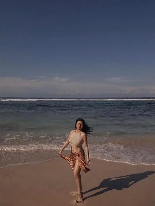 Dibantu oleh fashion stylist Aldi Indrajaya, perempuan 25 tahun ini tampil dengan beragam busana kekinian yang stylish. Seperti potret yang satu ini, dia tampil stylish memadukan nude  halter neck crop top dan kain lilit warna coklat. (Instagram/arieltatum/anaditya_).