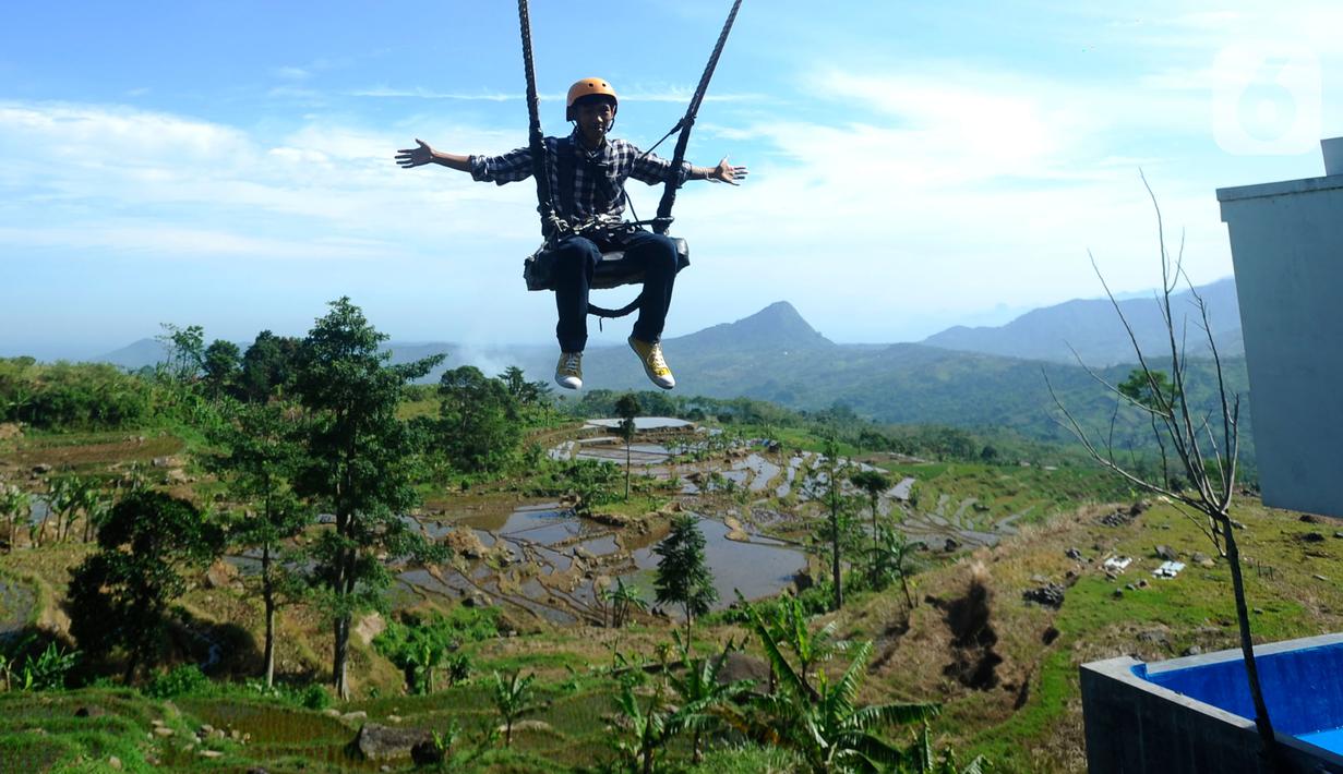 Wisatawan menaiki wahana ayunan saat mengunjungi tempat wisata yang Instagrammable di kawasan Puncak Dua, Sukamakmur, Bogor, Jumat (6/1/2023). Meski kawasan Puncak Dua belum dikembangkan secara maksimal oleh Pemkab Bogor dan pemerintah pusat, warga seputar Jabodetabek dan Cianjur tetap antusias mengunjungi kawasan ini sebagai tempat wisata alternatif selain kawasan Puncak dan sekitarnya yang selalu didominasi kemacetan lalu lintas. (merdeka.com/Arie Basuki)