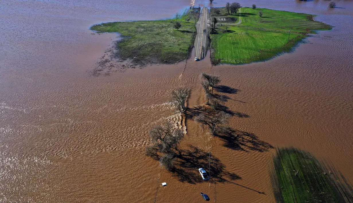 Tiga kendaraan terendam banjir setelah hujan lebat pada Malam Tahun Baru yang menyebabkan tanggul jebol di Dillard Road, Wilton, California, Amerika Serikat, 1 Januari 2023. Badai dahsyat yang menerjang California menyebabkan banjir, pohon tumbang, hingga tanah longsor. (Hector Amezcua/The Sacramento Bee via AP)