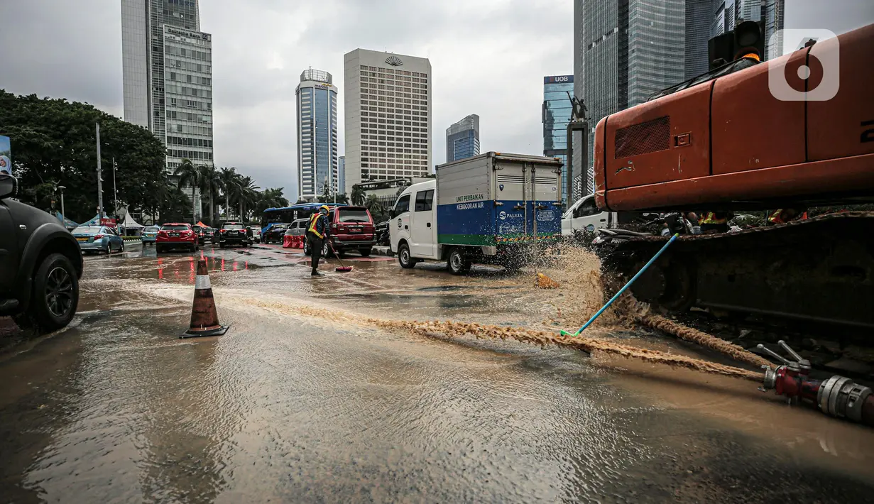 Petugas membersihkan jalan dari genangan air akibat kebocoran saluran pipa air di kawasan Bundaran Hotel Indonesia (HI), Jakarta, Selasa (11/10/2022). Kebocoran pipa air diduga terimbas proyek revitalisasi Halte Bundaran Hotel Indonesia. (Liputan6.com/Faizal Fanani)