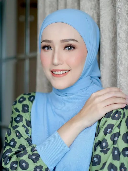 Potret close up bak boneka hidup dari Adelia Pasha. Ia mengenakan outfit cerah, yaitu atasan bernuansa kehijauan dengan motif bunga yang cantik, dipadu hijab biru muda. [Foto: Instagram/adeliapasha]