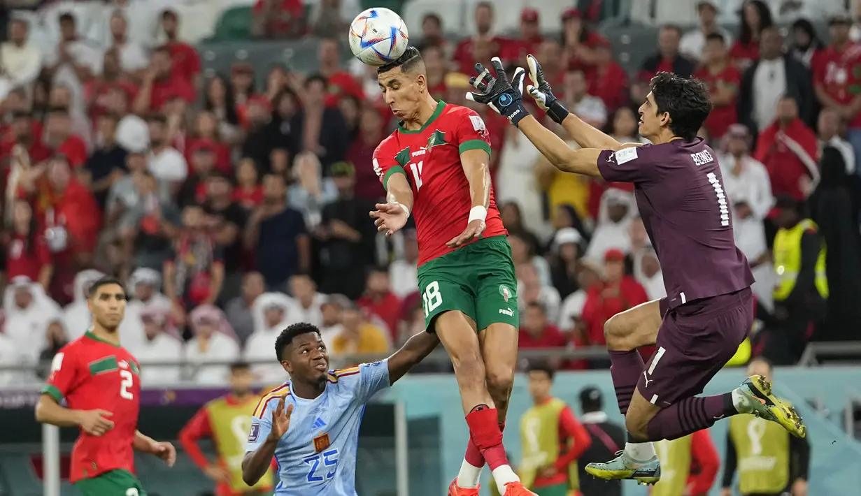 Bek dan kiper Maroko, Jawad El Yamiq dan Yassine Bounou meraih bola pada babak 16 besar Piala Dunia 2022 di Education City Stadium, Al Rayyan, Rabu (6/12/2022) dini hari WIB. Maroko melewati duel alot 120 menit untuk mengalahkan Spanyol di babak adu penalti dengan skor telak 3-0. (AP Photo/Julio Cortez)