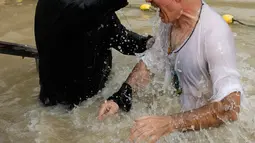 Seorang pria Kristen Ortodoks Serbia dibaptis di perairan Sungai Yordan di dekat kota Jericho (4/3). Sungai ini diyakini menjadi tempat Yesus Kristus dibaptis oleh Yohanes Pembaptis. (AFP Photo/Gali Tibbon)