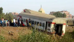 Orang-orang berkumpul di lokasi kecelakaan kereta penumpang dekat Banha, Provinsi Qalyubia, Mesir, Minggu (18/4/2021). Kecelakaan terjadi saat kereta berangkat dari Kairo menuju Kota Nile Delta. (AP Photo/Tarek Wagih)