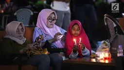 Pengunjung menyalakan lilin mendukung Earth Hour 2019 di Lippo Mall Kemang, Jakarta, Sabtu (30/3). Sebanyak 70 mal yang dikelola Lippo Malls Indonesia serentak memadamkan lampu eksterior dan 50% lampu penerangan di dalam gedung dari pukul 20:30 - 21:30 waktu setempat. (Liputan6.com/Fery Pradolo)
