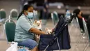 Seorang wanita menempatkan salah satu anjingnya ke dalam kereta bayi di Pet Expo Thailand 2021 tahunan di Bangkok (25/11/2021). Pet Expo Thailand 2021 diselenggarakan dari 25-28 November 2021 mulai pukul 10.00-20.00. (AFP/Jack Taylor)