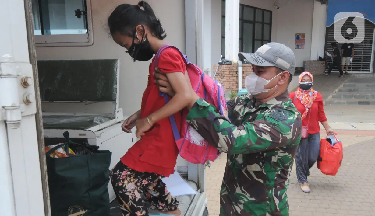 Anggota Kodiklat TNI membantu seorang anak menaiki kendaraan usai menjalani perawatan di Rumah Lawan Covid (RLC) di Tangerang Selatan, Kamis (5/8/2021). Dua pekan terakhir pasien Covid di RLC mengalami penurunan hingga 70 persen dari semula 300 pasien kini hanya 113 pasien. (merdeka.com/Arie Basuki)