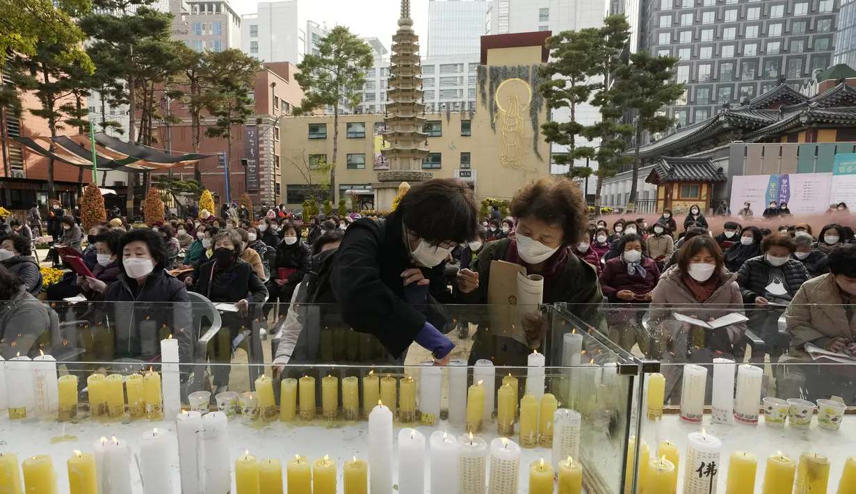 Seorang wanita menyalakan lilin untuk mendoakan kesuksesan anaknya dalam ujian masuk perguruan tinggi di kuil Buddha Jogyesa, Seoul, Rabu (17/11/2021). Sekitar 500.000 siswa SMA di Korea Selatan diperkirakan akan mengikuti Tes Kemampuan Skolastik Perguruan Tinggi. (AP Photo/Ahn Young-joon)