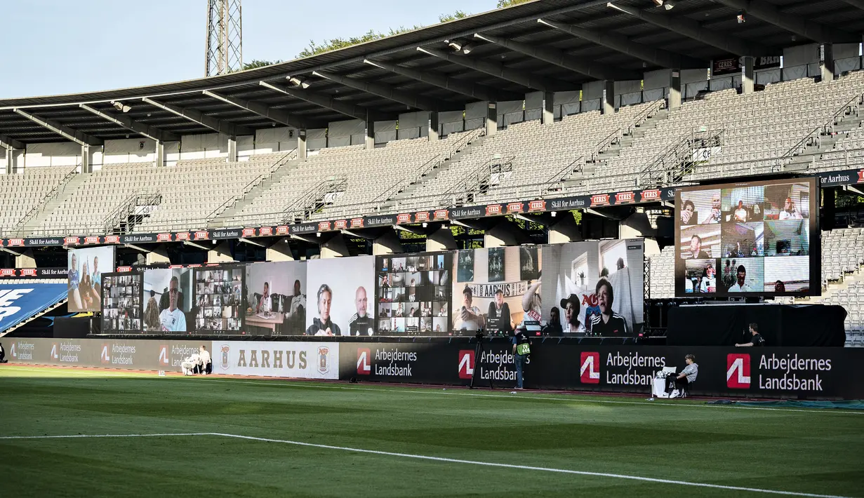 Penonton menyaksikan pertandingan Liga Denmark antara AGF dengan Randers FC melalui aplikasi video conference di Ceres Park, Aarhus, Denmark, Kamis (28/5/2020). Laga ini menjadi pertandingan pertama yang melibatkan suporter melalui aplikasi pertemuan virtual. (Henning Bagger/Ritzau Scanpix via AP)