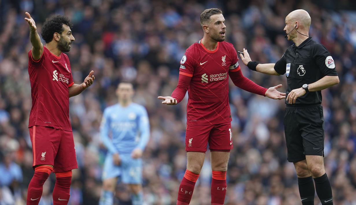 Wasit Anthony Taylor (kanan) berdiskusi dengan pemain Liverpool Jordan Henderson (tengah) dan Mohamed Salah saat pertandingan Liga Inggris antara Manchester City dan Liverpool di Etihad Stadium, 10 April 2022. (AP/Jon Super)