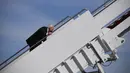 Presiden AS Joe Biden saat menaiki Air Force One di Pangkalan Udara Andrews, Maryland, Jumat (19/3/2021). Biden awalnya menaiki anak tangga dengan lancar tetapi sekitar setengah jalan menuju pesawat kepresidenan, dia tiba-tiba tersandung. (Eric BARADAT/AFP)