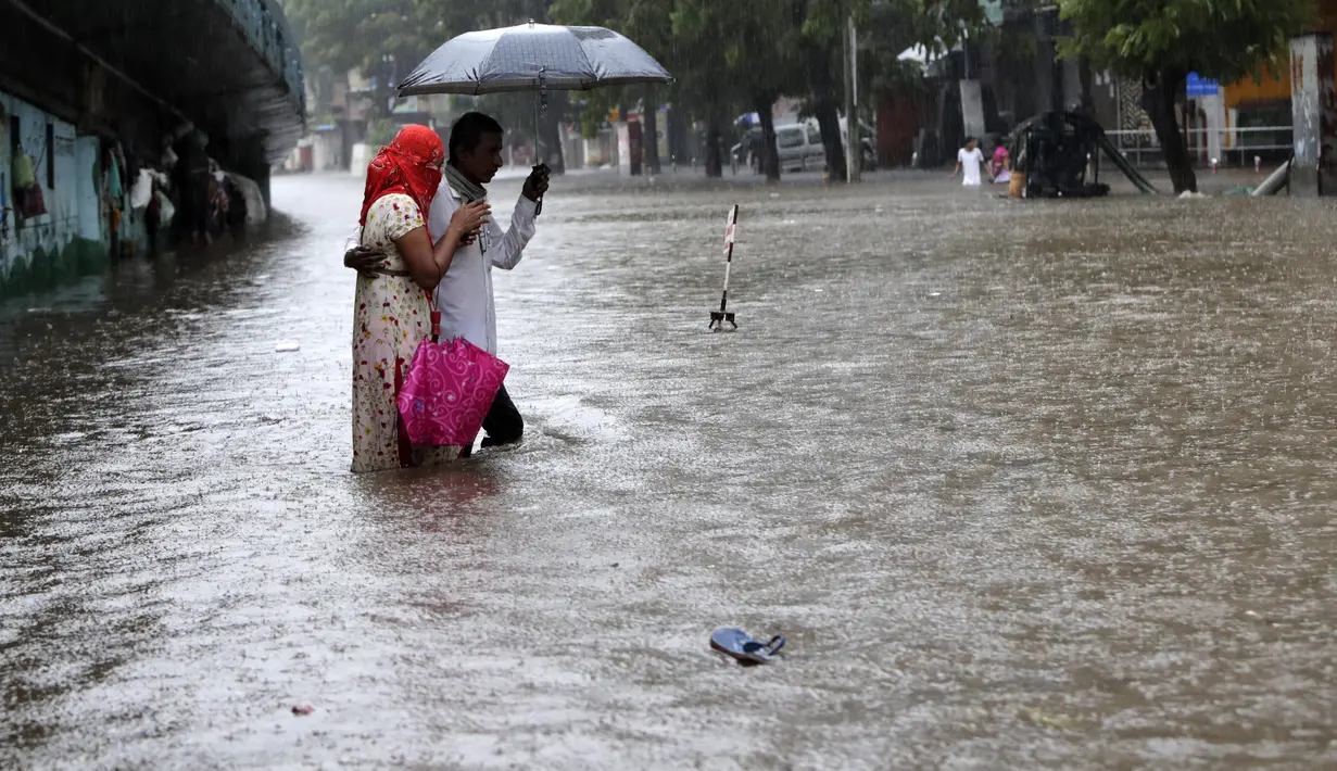 Orang-orang menyeberang jalan melintasi banjir saat hujan lebat di Mumbai, India, Rabu, (5/8/2020). Musim hujan India berlangsung dari Juni hingga September. (AP Photo/Rajanish Kakade)
