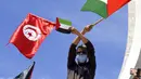 Warga Tunisia mengibarkan bendera Tunisia dan bendera Palestina saat protes untuk mendukung warga Palestina di Jalur Gaza di Tunis, Tunisia, Sabtu (15/5/2021). Serangan udara Israel menghancurkan gedung bertingkat tinggi di Kota Gaza yang menjadi kantor AP dan media lainnya. (AP Photo/Hassene Dridi)