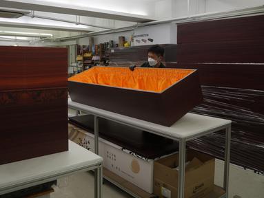 Seorang pekerja memindahkan peti mati kertas di pabrik LifeArt di Hong Kong pada Jumat, 18 Maret 2022. Hong Kong kehabisan peti mati selama wabah paling mematikan dari pandemi virus corona covid-19. (AP Photo/Kin Cheung)