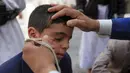 Seorang pria Yaman mengoleskan kosmetik tradisional Kohl ke kelopak mata remaja selama bulan puasa Ramadhan di Masjid Sanaa (16/4/2021).  Umat Muslim di Yaman percaya bahwa kohl atau celak mampu membersihkan dan melindungi mata dari berbagai penyakit. (AFP/ Mohammed Huwais)