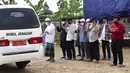 Para pria berdoa dekat ambulans yang membawa jenazah korban COVID-19 di TPU Rorotan, Jakarta, Rabu (7/7/2021). Pemakaman harian di Ibu Kota telah meningkat berlipat ganda di tengah lonjakan pesat kasus COVID-19 dalam beberapa minggu terakhir. (AP Photo/Tatan Syuflana)
