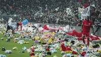 Pemain Besiktas dan Antalyaspor dibantu petugas mengumpulkan boneka yang dilemparkan oleh penonton pada laga lanjutan Liga Turki 2022/2023 yang berlangsung di Stadion Vodafone, Istanbul, Minggu (27/02/2023). Aksi tersebut ditujukan sebagai bentuk sumbangan untuk anak-anak korban gempa Turki. (AP Photo)