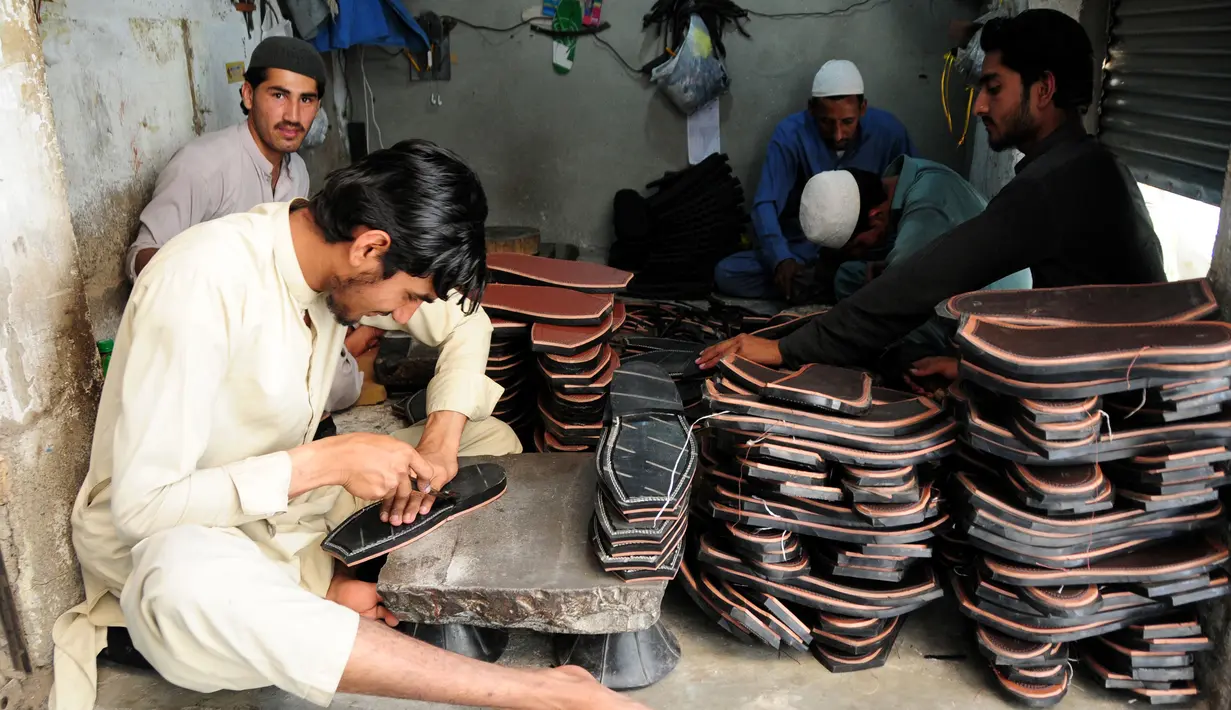 Seorang pembuat sepatu asal Pakistan membuat sepatu tradisional yang dikenal sebagai "chapli" di kalangan penduduk lokal untuk menyambut Hari Raya Idul Fitri di Peshawar, Pakistan barat laut, pada 19 Mei 2020. (Xinhua/Saeed Ahmad)