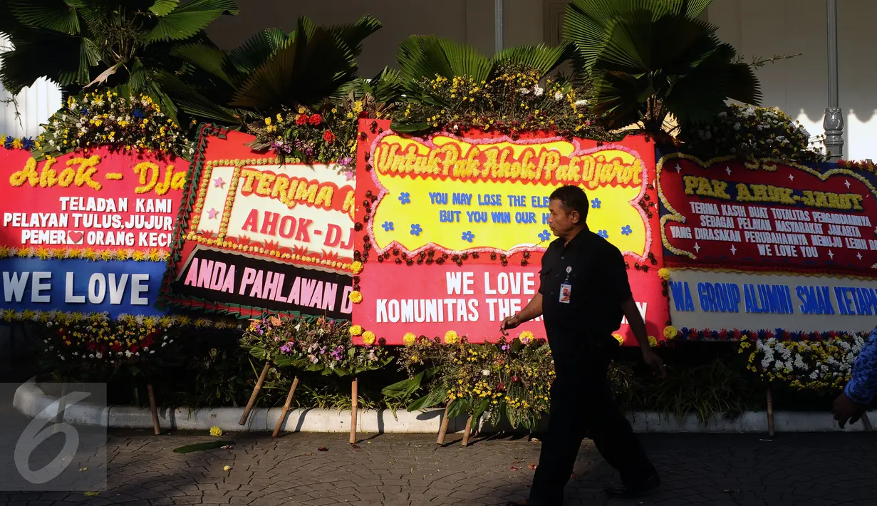 Petugas melintas di depan karangan bunga untuk Gubernur DKI Jakarta Basuki Tjahaja Purnama dan Wagub Djarot Sjaiful Hidayat di halaman Balai Kota Jakarta, Selasa (25/4). Karangan bunga ini berisi pernyataan dukungan. (Liputan6.com/Helmi Fithriansyah)  