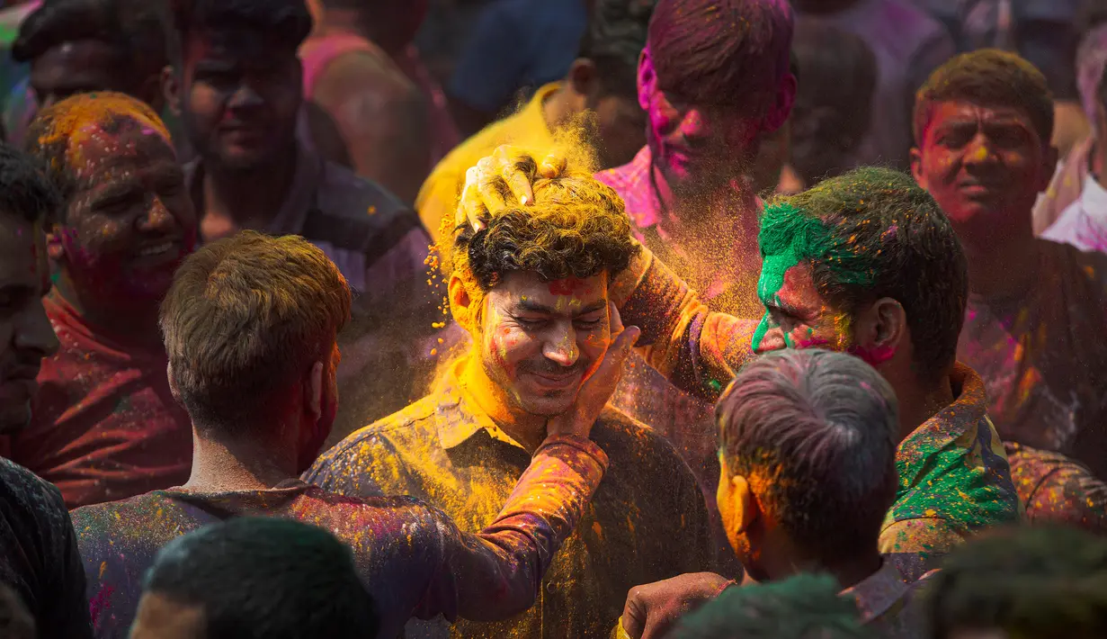 Orang-orang mengoleskan bubuk berwarna satu sama lain saat Festival Holi di Gauhati, India, Selasa (10/3/2020). Festival Holi menandai datangnya musim semi di India. (AP Photo/Anupam Nath)