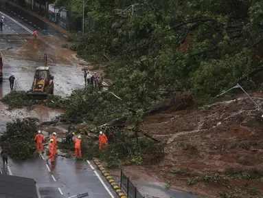 Petugas pemadam kebakaran membersihkan jalan setelah tanah longsor yang disebabkan oleh curah hujan di Mumbai, India, Rabu, (6/8/2020). Musim hujan India berlangsung dari Juni hingga September. (AP Photo / Rafiq Maqbool)