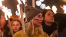 Seorang wanita memegang obor saat demonstrasi untuk Ukraina yang diselenggarakan oleh Greenpeace di Heroes Square, Budapest, Hungaria, 9 Maret 2022. Invasi Rusia ke Ukraina telah memicu migrasi massal terbesar di Eropa dalam beberapa dekade. (AP Photo/Anna Szilagyi)