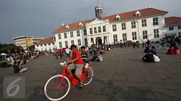 Warga berwisata menaiki sepeda kuno di kawasan Kota Tua, Jakarta, Minggu (8/5). Meskipun libur panjang akan berakhir, Warga tetap memadati kawasan wisata Kota Tua. (Liputan6.com/Immanuel Antonius)