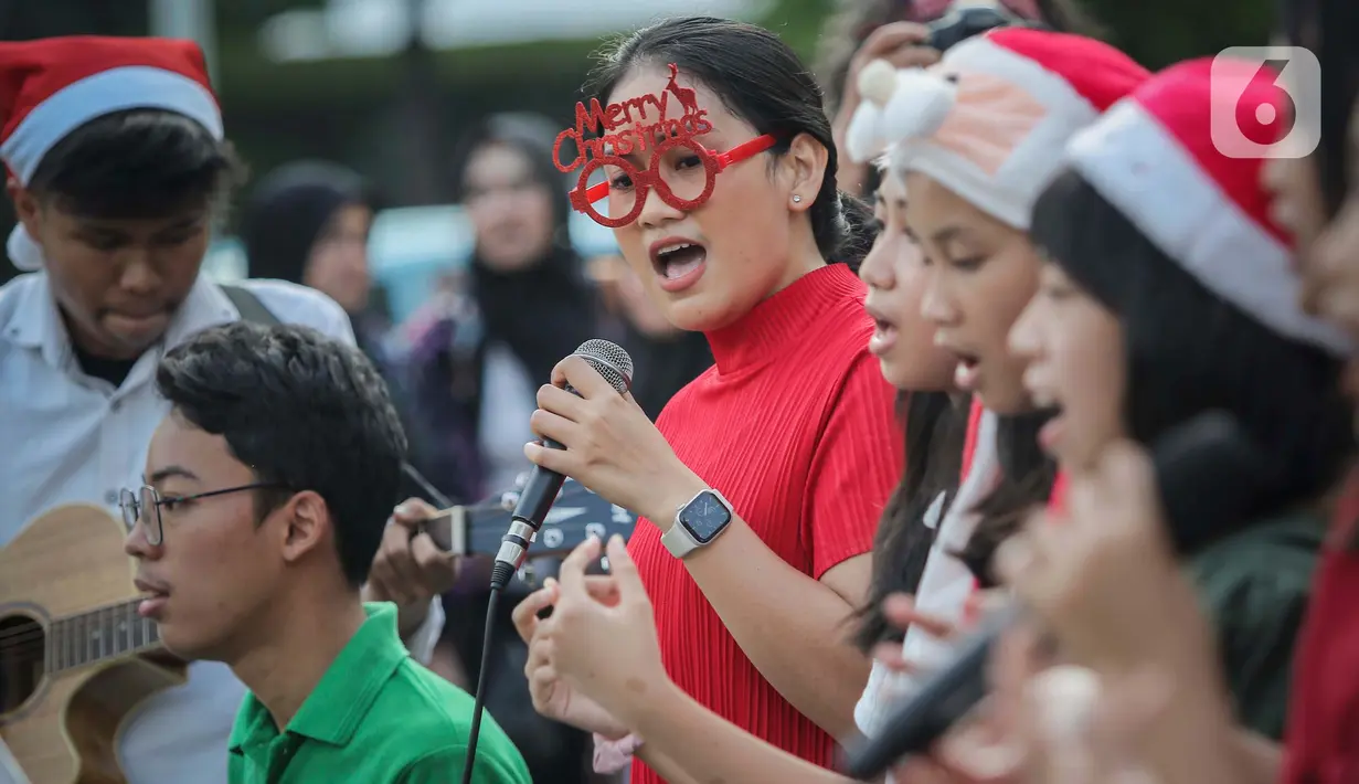 Paduan suara Sekolah Minggu Gereja Toraja Depok saat menyanyikan lagu lagu rohani di Bundaran HI, Jakarta, Jumat (22/12/2023). (Liputan6.com/Angga Yuniar)