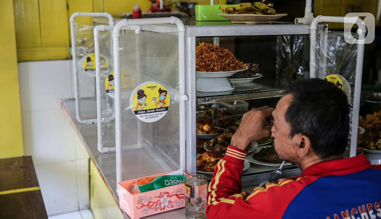 Pengunjung makan di Warteg Ellya yang menerapkan protokol kesehatan pencegahan penyebaran COVID-19, Cilandak Timur, Pasar Minggu, Jakarta, Selasa (21/7/2020). Warteg Ellya menerapkan protokol kesehatan pencegahan penyebaran COVID-19 sejak penerapan PSBB transisi. (Liputan6.com/Faizal Fanani)