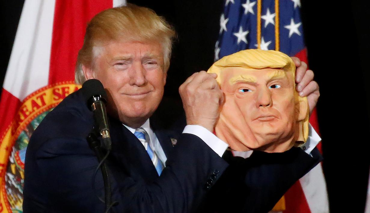 Ekspresi Donald Trump saat menunjukan topeng wajah dirinya ke awak media saat berkampanye di Sarasota, Florida, AS (7/11). Pilpres AS 2016 akan diadakan pada 8 November 2016 dan menjadi pilpres empat tahunan ke-58.  (REUTERS/Carlo Allegri) 